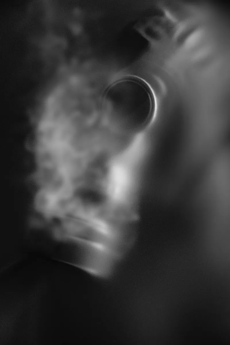 Blurred black and white photograph of a face with a gas mask, motion-blurred and ghostly